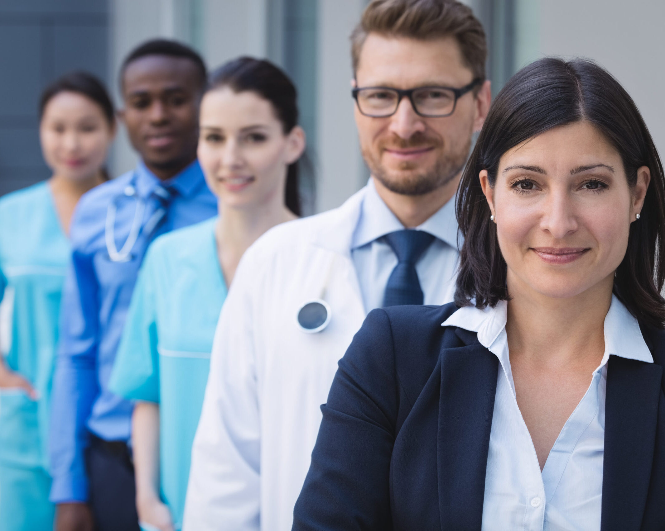 Portrait of smiling doctors standing in row at hospital premises